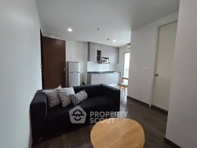 Modern open-plan living room with kitchen, featuring sleek furniture and appliances.