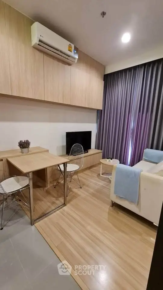 Modern living room with sleek wooden flooring, cozy seating, and stylish decor in a contemporary apartment.
