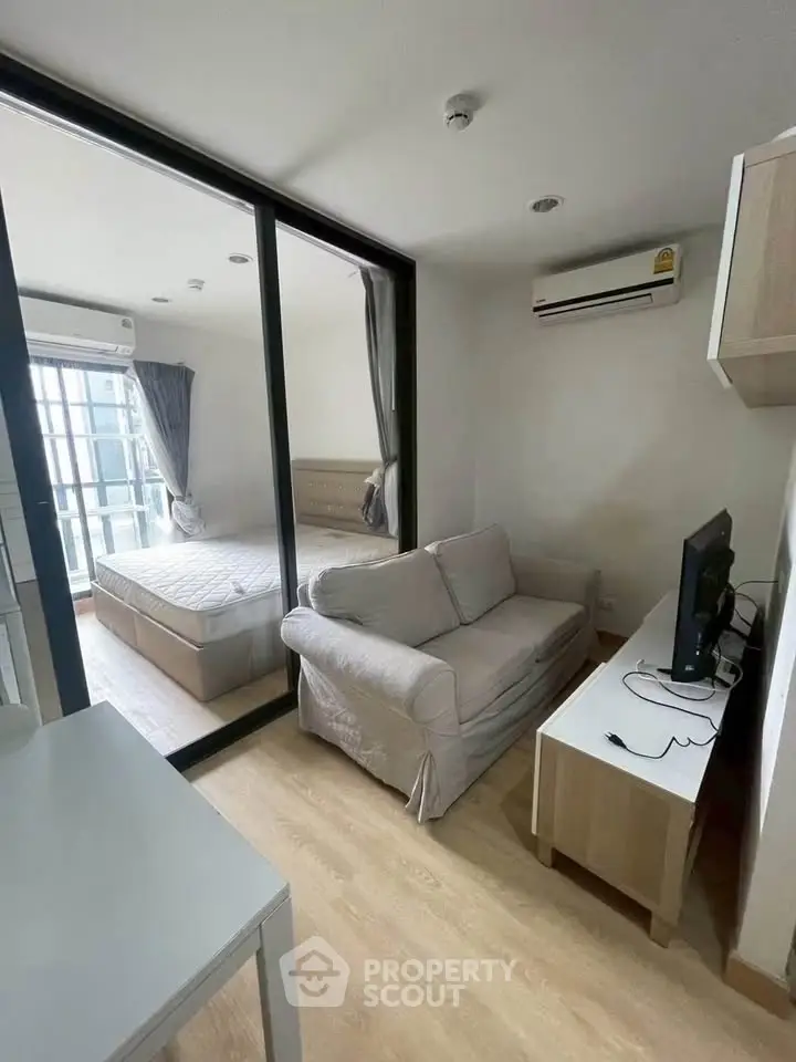 Modern studio apartment with cozy living area and bedroom separated by glass partition.