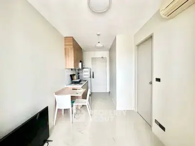 Modern minimalist kitchen with sleek cabinetry and dining area in compact apartment.