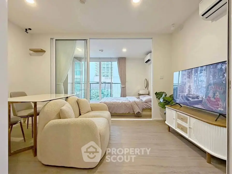 Modern open-plan living room with cozy seating and view into stylish bedroom