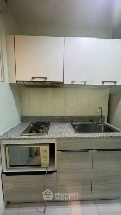 Compact kitchen with modern cabinetry and built-in appliances in a cozy apartment.