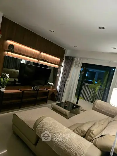 Luxurious living room with modern decor and large TV, perfect for relaxation and entertainment.