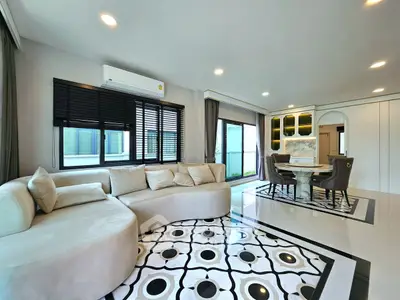 Luxurious living room with modern decor and elegant dining area, featuring large windows and stylish furnishings.
