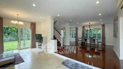 Spacious open-plan living and dining area with garden view, elegant lighting, and polished wooden floors.