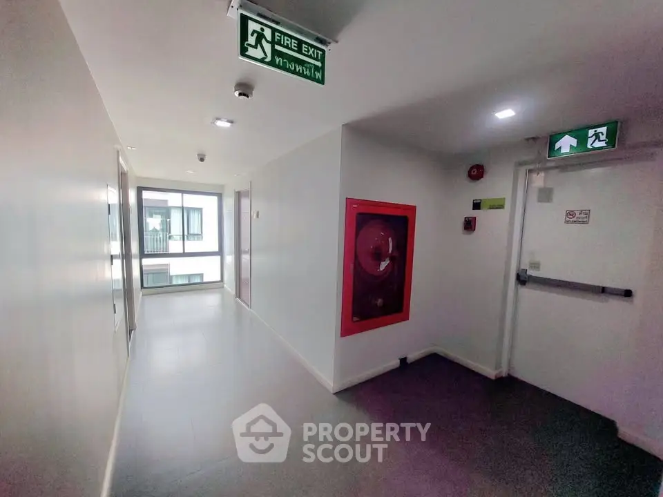 Modern building corridor with fire safety equipment and exit signs, showcasing secure and well-maintained common areas.