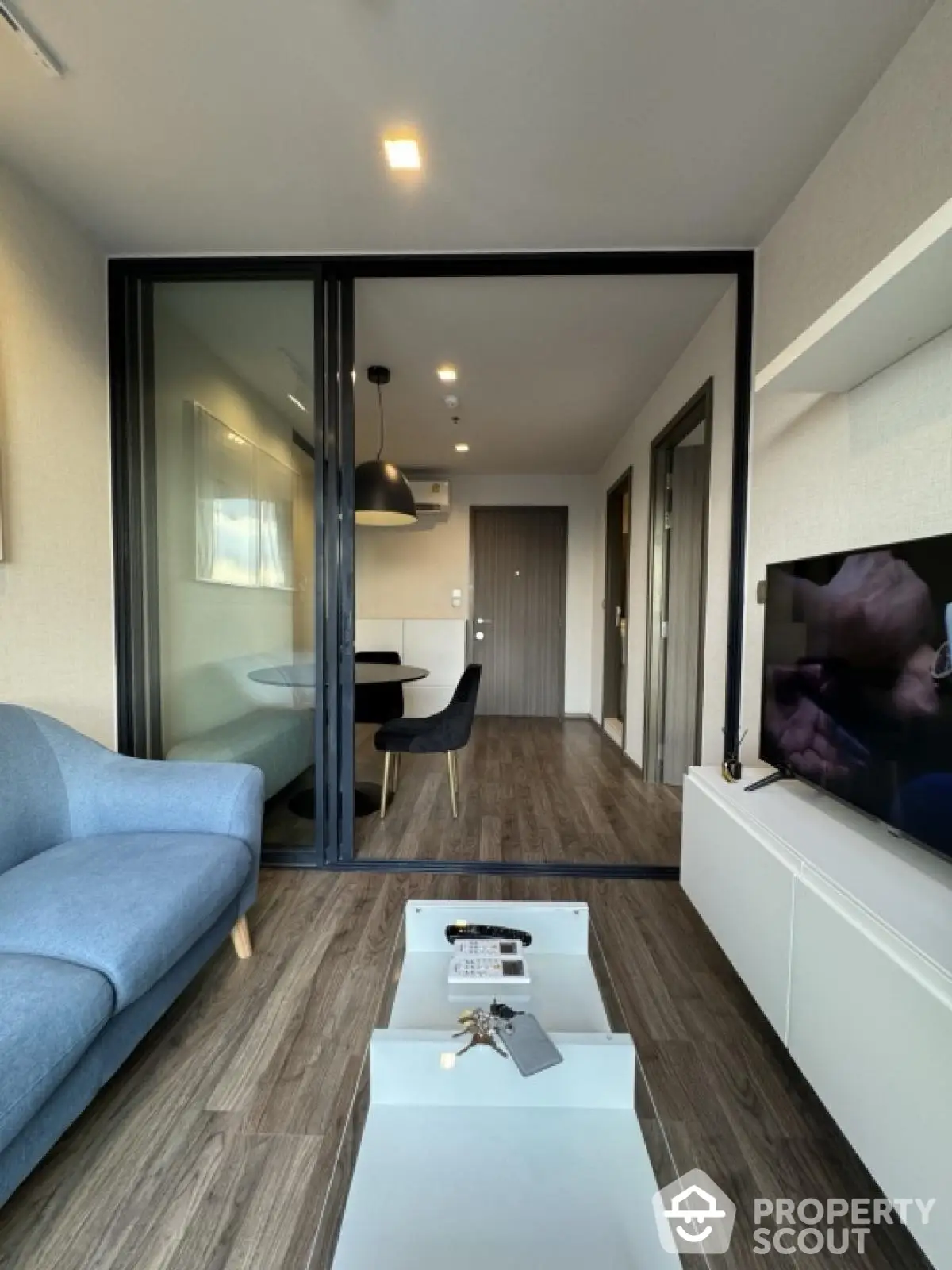 Modern living room with sleek furniture and open layout, featuring a cozy blue sofa and stylish decor.