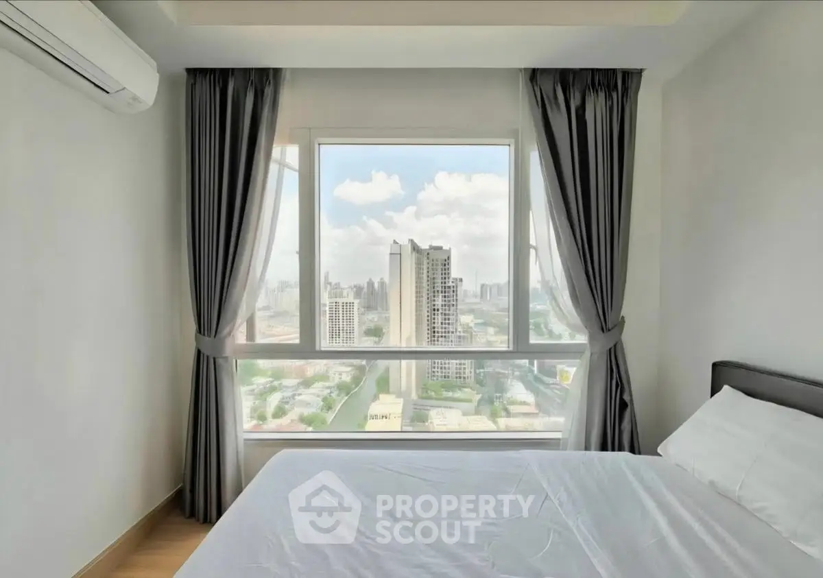 Bright bedroom with large window offering stunning city view in modern high-rise apartment.