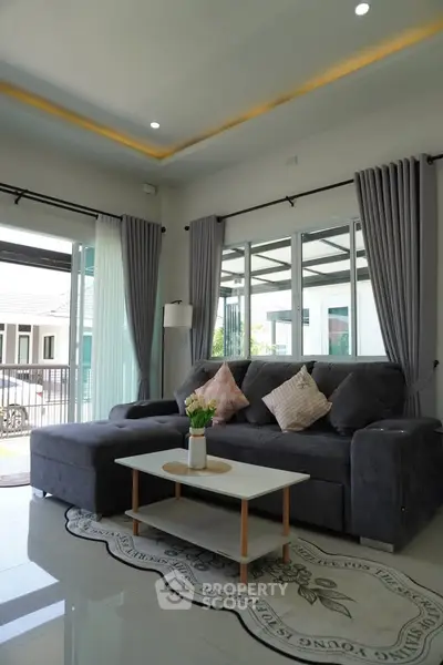 Modern living room with large windows, stylish gray sofa, and elegant decor in a bright, airy space.