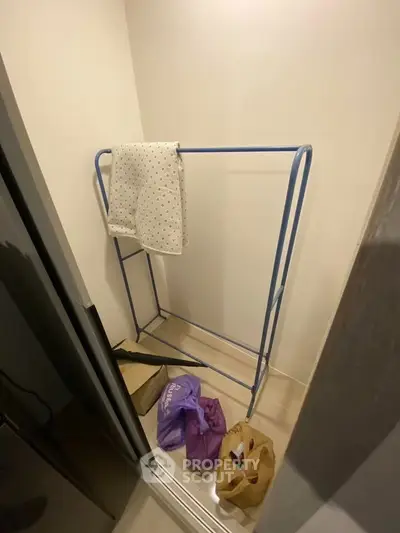 Compact storage space with clothes rack and shopping bags, ideal for organizing small apartments.
