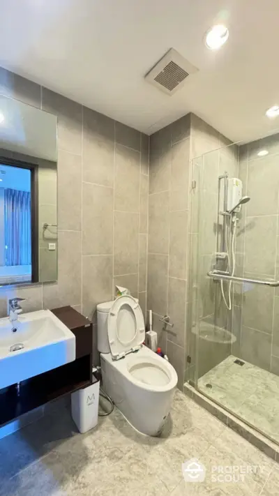 Modern bathroom with glass shower and sleek fixtures in contemporary apartment.