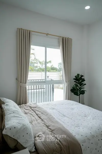 Cozy bedroom with large window and elegant curtains, offering a serene view and natural light.