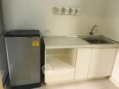 Compact kitchen with modern fridge and sleek countertop in cozy apartment.
