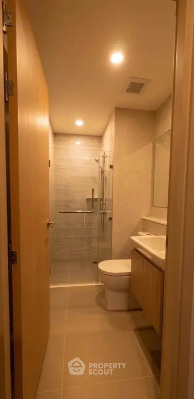 Modern bathroom with sleek fixtures and glass shower enclosure in a contemporary apartment.