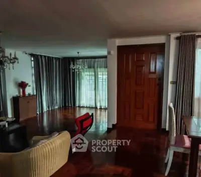 Spacious living room with elegant wooden flooring and large windows with curtains.