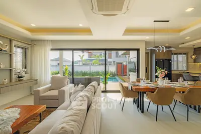 Luxurious open-plan living and dining area with modern decor and pool view, perfect for entertaining.