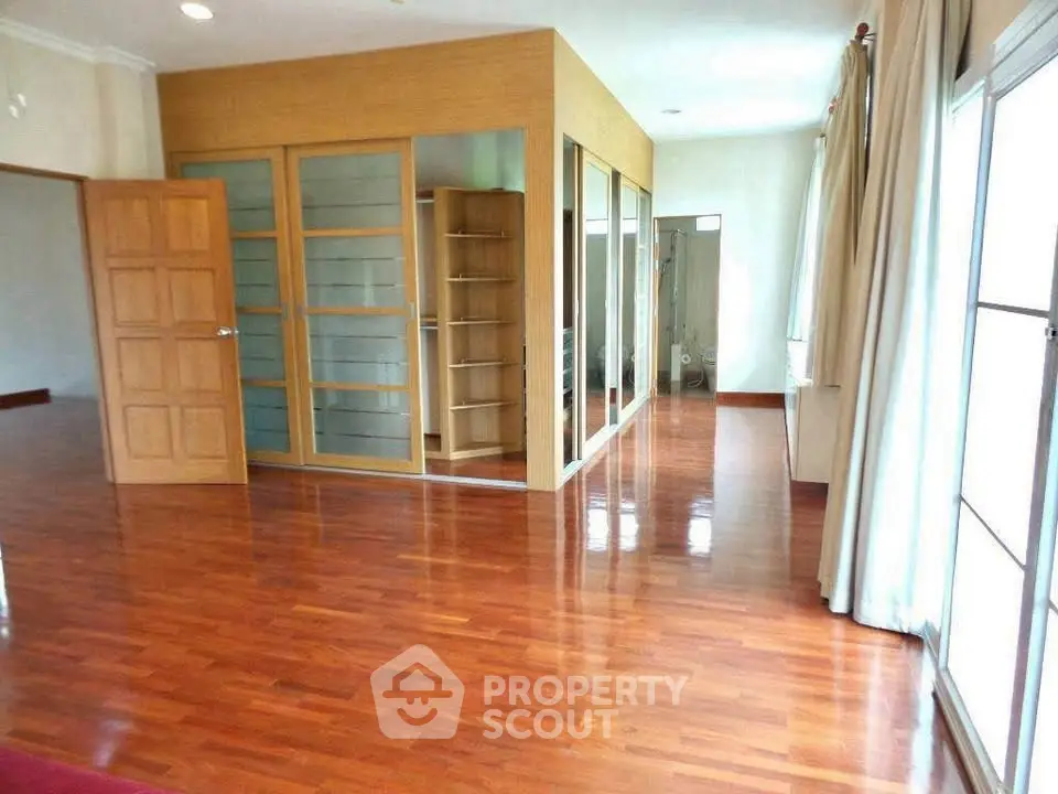Spacious room with wooden flooring and large windows in a modern home.