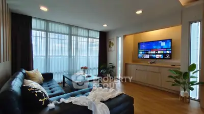 Spacious modern living room with large windows and sleek entertainment setup.