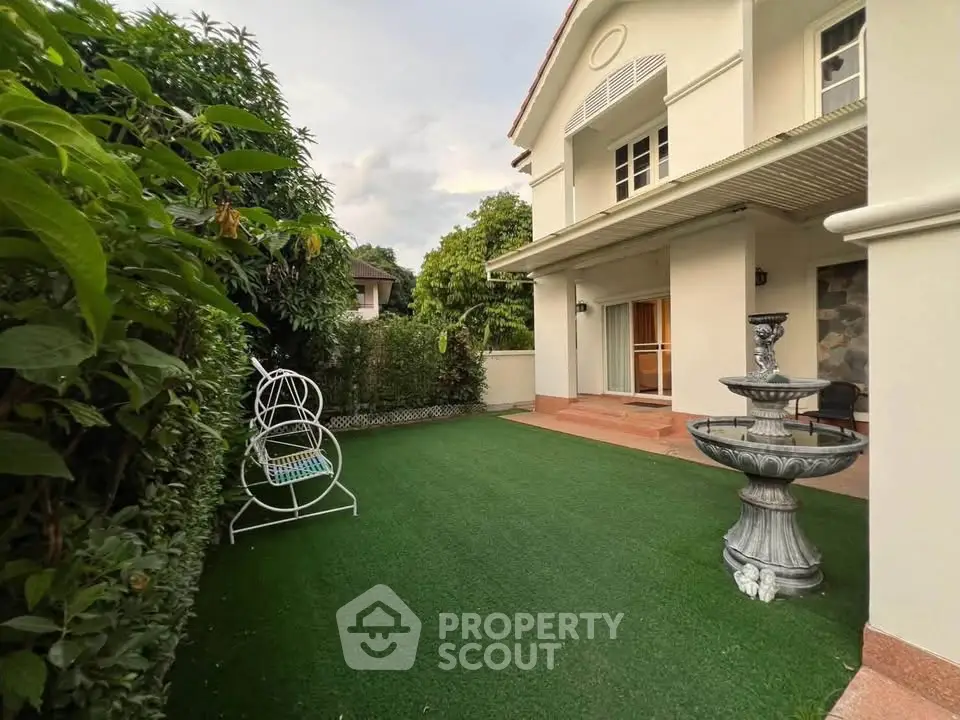 Charming house with lush garden and elegant fountain, perfect for serene outdoor living.