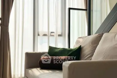 Cozy living room with elegant sofa and natural light through large windows.