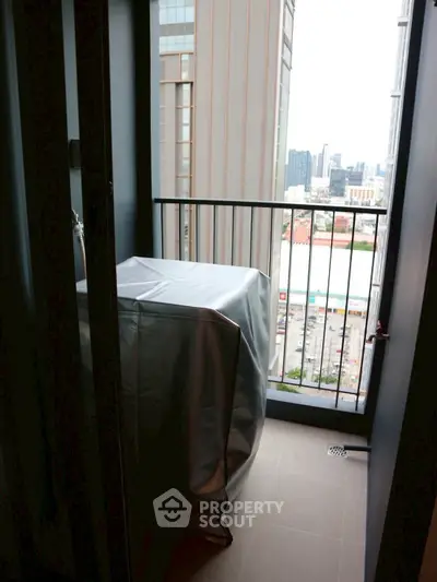 Urban balcony with city view, featuring covered appliance and modern railing.
