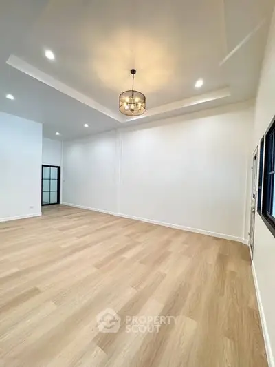 Spacious modern living room with elegant lighting and hardwood floors.
