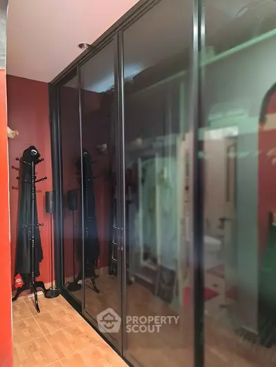 Spacious walk-in closet with sleek mirrored sliding doors and elegant coat racks.