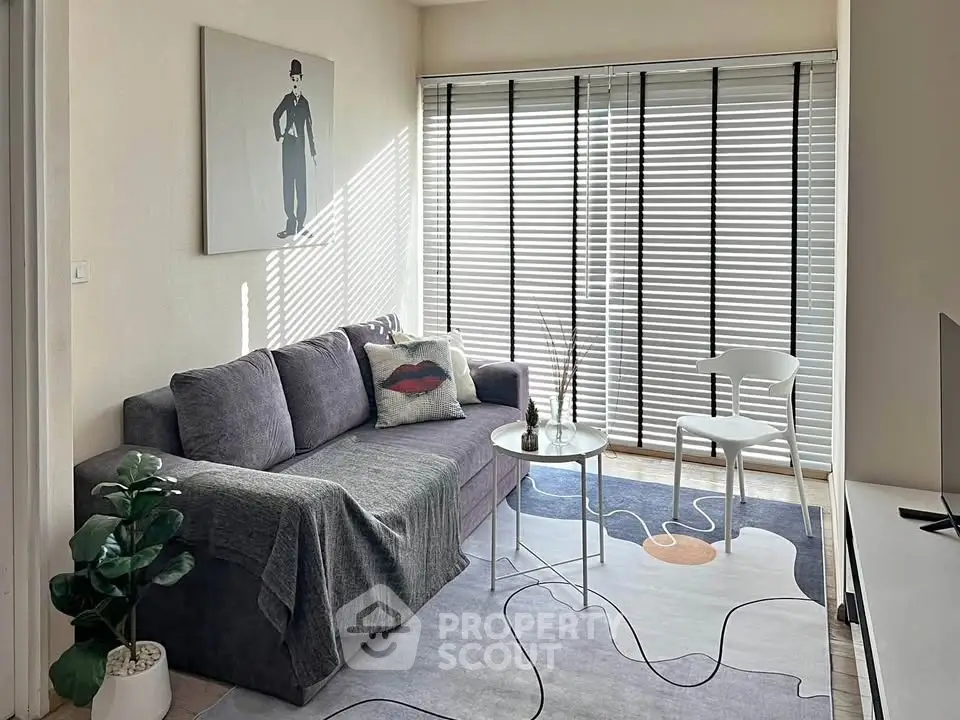 Chic living room with modern decor, featuring a cozy gray sofa, stylish artwork, and abundant natural light.