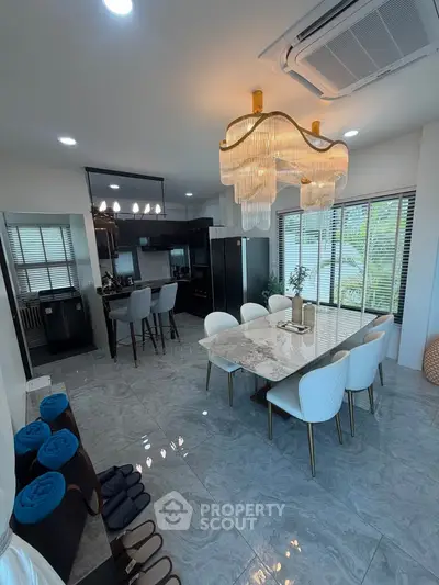 Luxurious dining area with elegant chandelier and modern kitchen in open layout design.