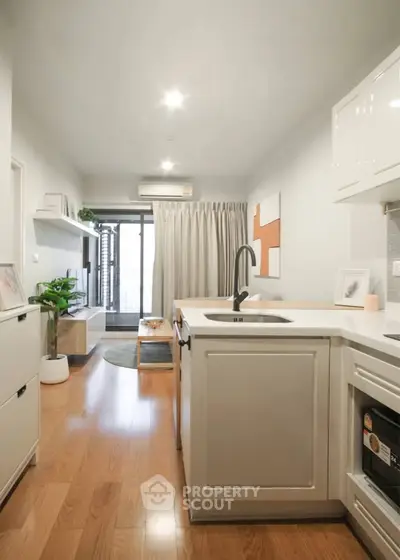 Modern open-layout kitchen and living room with wooden flooring and stylish decor.