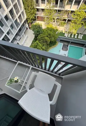 High-rise balcony with a serene view overlooking a communal pool and lush greenery, perfect for relaxing outdoor moments in a modern urban residence.