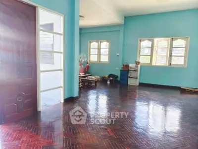 Spacious living room with polished wooden floors and large windows in a bright, airy home.
