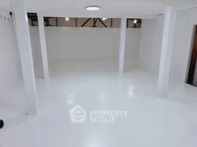 Spacious white basement with open layout and modern lighting