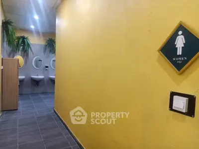 Modern public restroom with yellow walls and stylish sinks, ideal for commercial spaces.