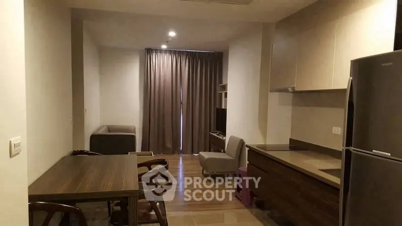 Modern apartment interior with open kitchen and cozy living area, featuring sleek furniture and natural lighting.