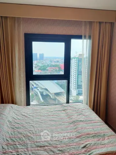 Cozy bedroom with city view from window, ideal for urban living.