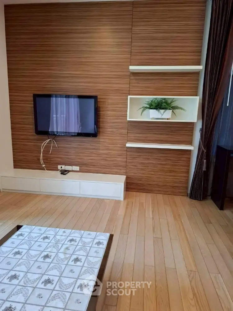 Modern living room with wooden panel wall and built-in TV, featuring elegant decor.