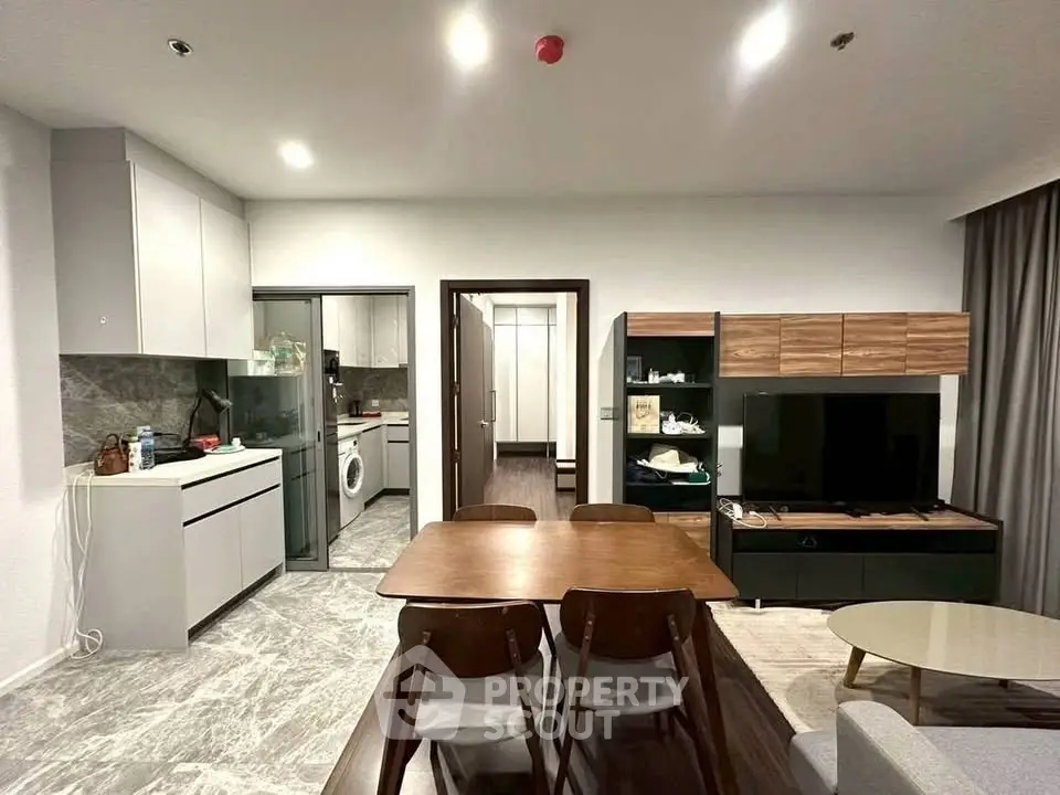 Modern living room with open kitchen and stylish dining area in contemporary apartment.