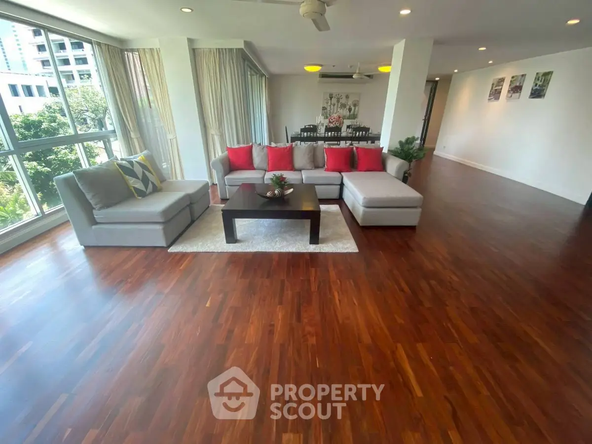 Spacious living room with hardwood floors and large windows in modern apartment