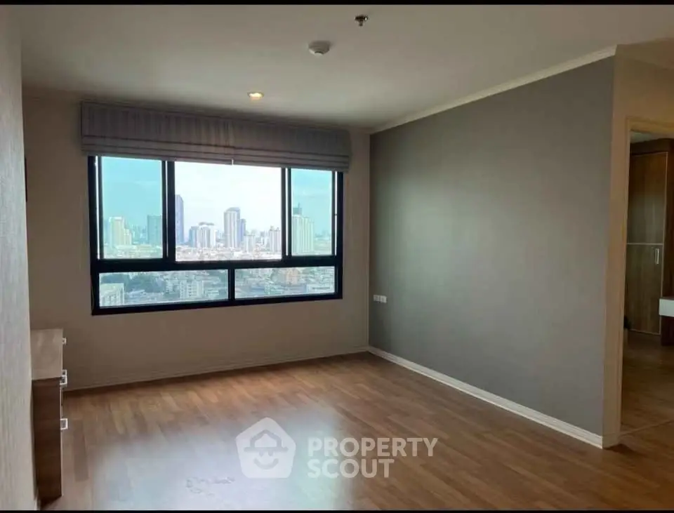 Spacious empty room with large window offering stunning city skyline view, perfect for customization.