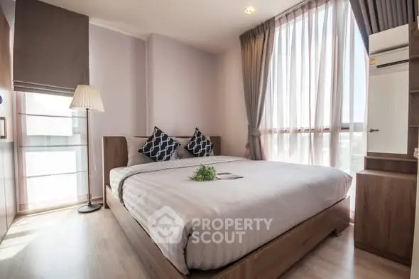 Modern bedroom with large windows and stylish decor, featuring a cozy bed and elegant lighting.