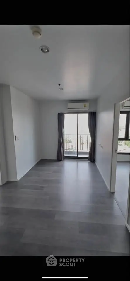 Spacious modern living room with balcony access and sleek flooring, perfect for urban living.