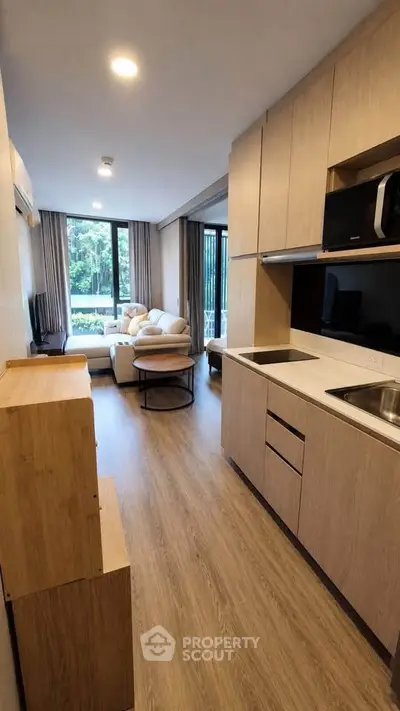 Modern open-layout kitchen and living room with natural light and stylish furnishings.