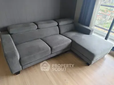 Modern gray sectional sofa in a bright living room with city view.