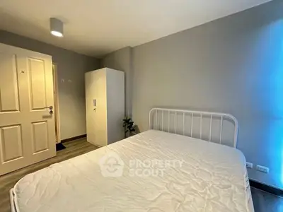 Cozy minimalist bedroom with white bedframe and wardrobe, perfect for modern living.