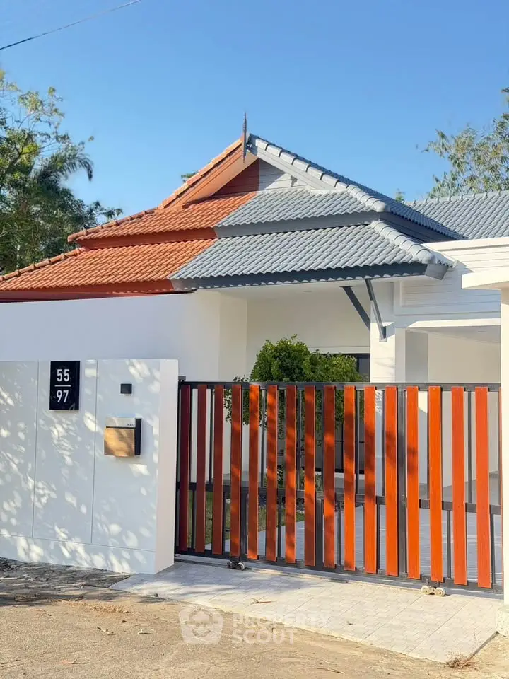 Charming modern house with unique roof design and wooden gate in a serene neighborhood.