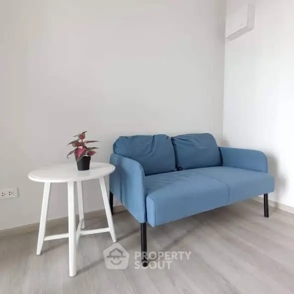 Modern living room with blue sofa and white side table, minimalist design.