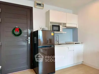 Modern compact kitchen with fridge and microwave in cozy apartment