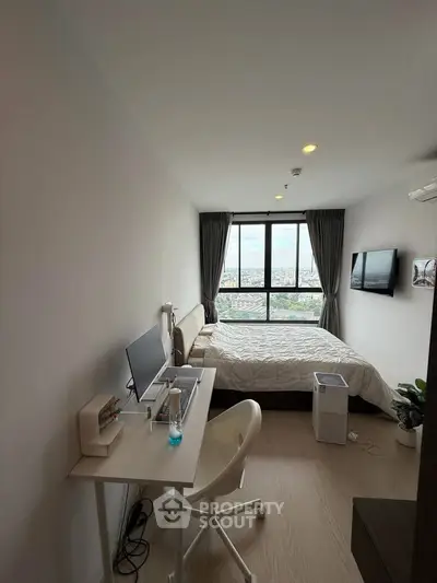 Modern bedroom with city view, featuring a sleek desk setup and cozy bed.