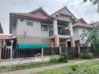 Charming two-story house with red-tiled roof and fenced yard in a serene neighborhood.